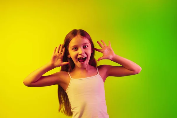 Pequenas meninas caucasianas retrato isolado no fundo gradiente em luz de néon. Conceito de emoções humanas, expressão facial, gadgets modernos e tecnologias. Espaço de cópia . — Fotografia de Stock
