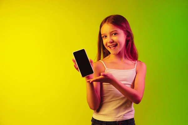 Pequenas meninas caucasianas retrato isolado no fundo gradiente em luz de néon. Conceito de emoções humanas, expressão facial, gadgets modernos e tecnologias. Espaço de cópia . — Fotografia de Stock