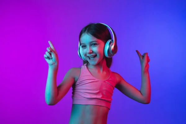 Kleine kaukasische Mädchen Porträt isoliert auf Gradienten rosa-blauen Hintergrund in Neonlicht. — Stockfoto
