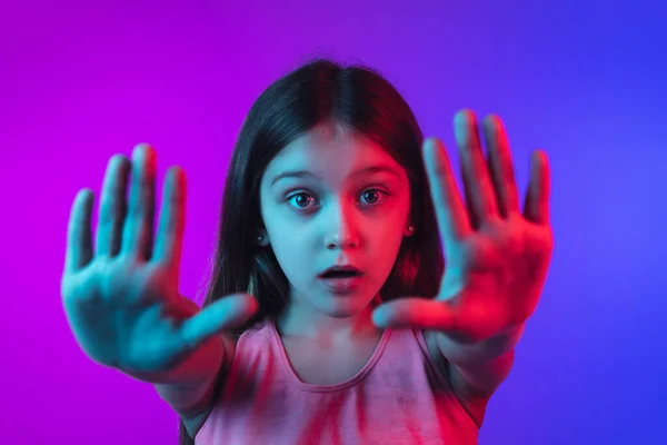 Malý kavkazský dívky portrét izolované na gradient růžovo-modré pozadí v neonovém světle. — Stock fotografie