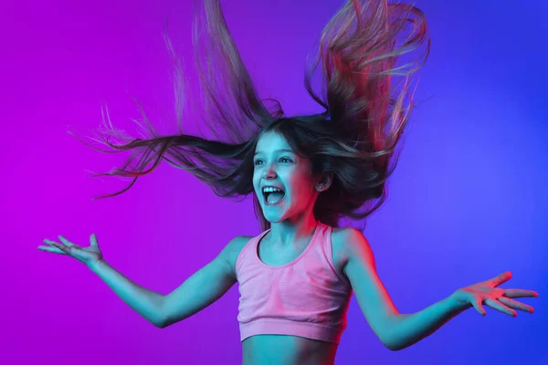 네온 빛을 받는 분홍빛 - 파란색 배경에 고립된 어린 코카서스 소녀 사진. — 스톡 사진
