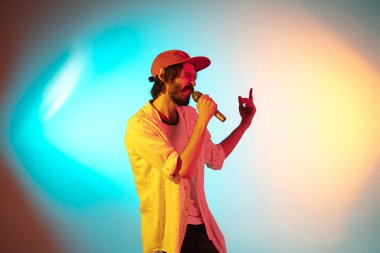 Beyaz tenli genç müzisyen neon ışıkta arka planda şarkı söylüyor. Müzik anlayışı, hobi, festival