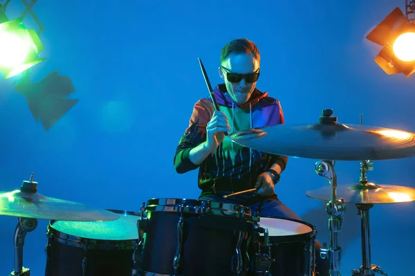 Jovem músico caucasiano tocando em fundo gradiente em luz de néon. Conceito de música, hobby, festival — Fotografia de Stock