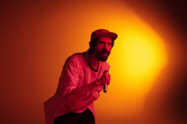 Beyaz tenli genç müzisyen neon ışıkta arka planda şarkı söylüyor. Müzik anlayışı, hobi, festival