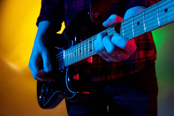 Joven músico caucásico tocando sobre fondo degradado en luz de neón. Concepto de música, hobby, festival — Foto de Stock