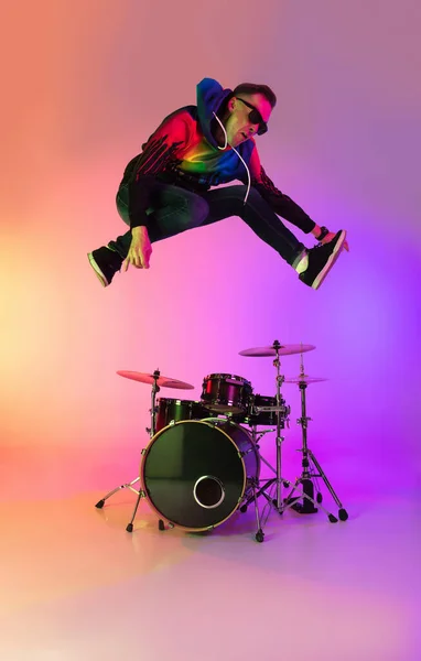 Jonge Kaukasische muzikant speelt op een gradiënt achtergrond in neon licht. Concept van muziek, hobby, festival — Stockfoto