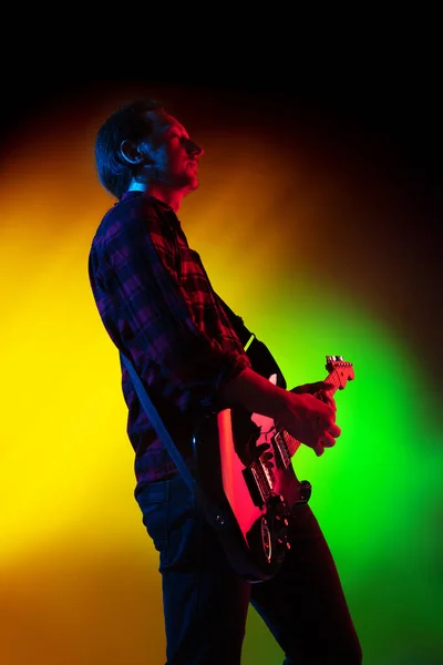 Junger kaukasischer Musiker spielt auf einem Gradienten-Hintergrund im Neonlicht. Konzept Musik, Hobby, Festival — Stockfoto