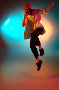 Beyaz tenli genç müzisyen neon ışıkta arka planda şarkı söylüyor. Müzik anlayışı, hobi, festival