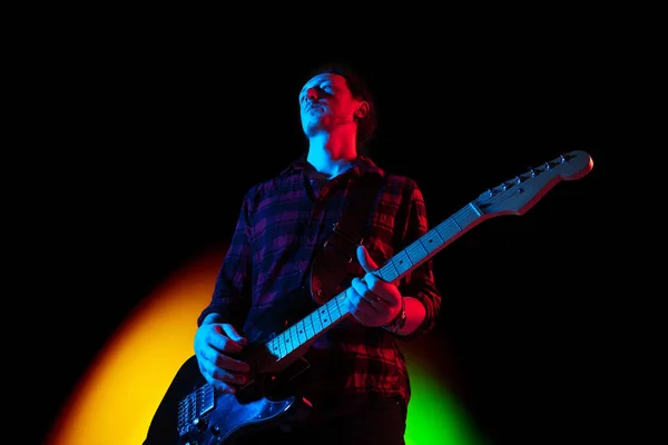 Jovem músico caucasiano tocando em fundo gradiente em luz de néon. Conceito de música, hobby, festival — Fotografia de Stock
