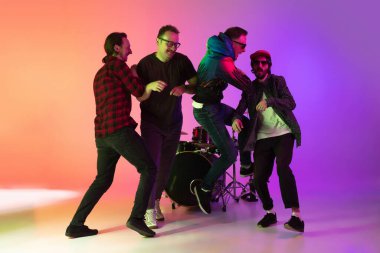 Genç müzisyenler, bando çalıyorlar, arka planda neon ışıklarıyla şarkı söylüyorlar. Müzik anlayışı, hobi, festival