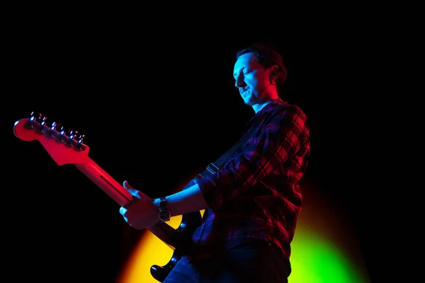 Joven músico caucásico tocando sobre fondo degradado en luz de neón. Concepto de música, hobby, festival —  Fotos de Stock