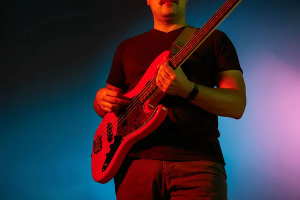 Jonge Kaukasische muzikant speelt op een gradiënt achtergrond in neon licht. Concept van muziek, hobby, festival — Stockfoto