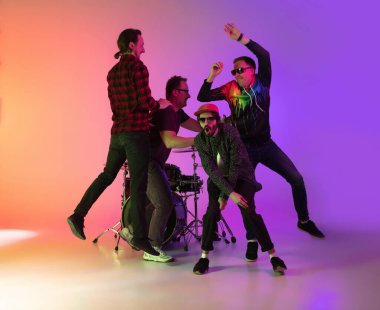 Genç müzisyenler, bando çalıyorlar, arka planda neon ışıklarıyla şarkı söylüyorlar. Müzik anlayışı, hobi, festival