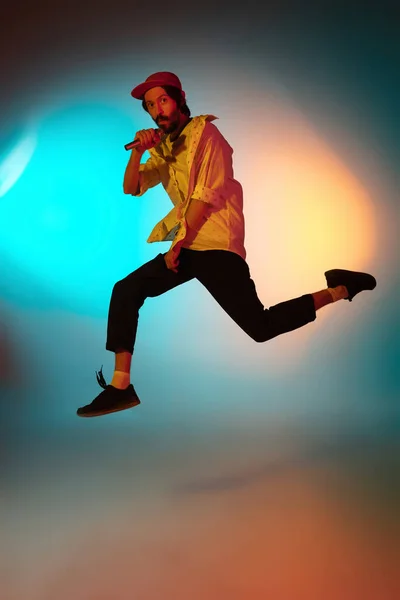 Jeune musicien caucasien jouant, chantant sur fond dégradé sous la lumière du néon. Concept de musique, passe temps, festival — Photo