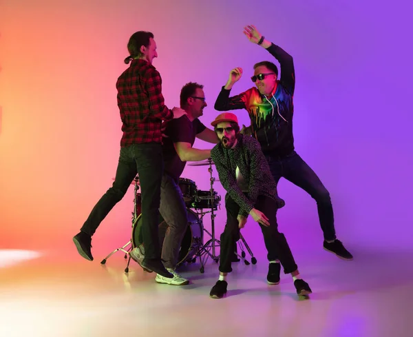 Mladí hudebníci, kapela hrající, vystupující na gradientním pozadí v neonovém světle. Koncept hudby, hobby, festival — Stock fotografie