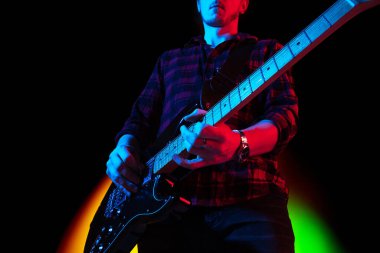 Beyaz tenli genç müzisyen, arka planda neon ışıklarıyla oynuyor. Müzik anlayışı, hobi, festival