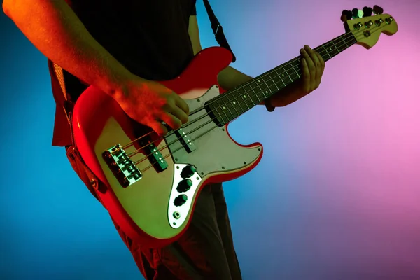 Jovem músico caucasiano tocando em fundo gradiente em luz de néon. Conceito de música, hobby, festival — Fotografia de Stock