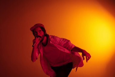 Beyaz tenli genç müzisyen neon ışıkta arka planda şarkı söylüyor. Müzik anlayışı, hobi, festival