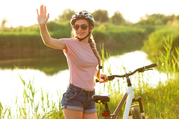 Joyful jonge vrouw rijden een fiets aan de rivier en weide promenade — Stockfoto