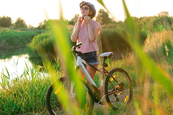 Радостная молодая женщина на велосипеде на берегу реки и луговой набережной — стоковое фото