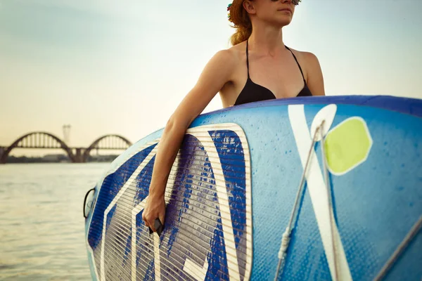 Mujer atractiva joven lleva paddle board, SUP. Vida activa, deporte, concepto de actividad de ocio —  Fotos de Stock