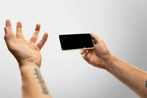 온라인상에서 인기있는 스포츠 경기와 세계 선수권 대회를 보는 동안, 남자 손을 빈 화면으로 핸드폰을 들고 닫아 둔다. 광고를 위한 복사 공간 — 스톡 사진