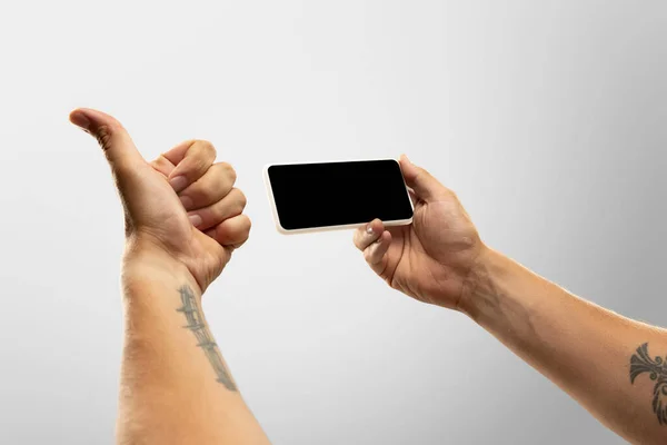 Primer plano manos masculinas sosteniendo el teléfono con pantalla en blanco durante la observación en línea de partidos deportivos populares y campeonatos de todo el mundo. Copyspace para anuncio —  Fotos de Stock