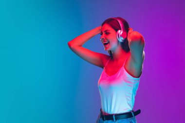 Caucasian young womans portrait isolated on gradient purple-blue background in neon light clipart