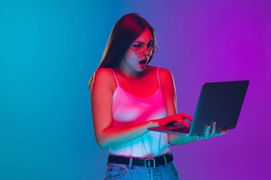 Caucasian young womans portrait isolated on gradient purple-blue background in neon light, cinema, movie watching clipart