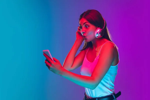 Mulheres brancas jovens retrato isolado no gradiente roxo-azul fundo em luz de néon — Fotografia de Stock