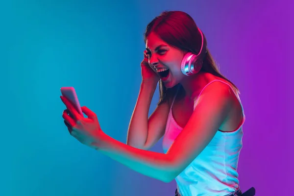 Caucasian young womans portrait isolated on gradient purple-blue background in neon light — Stock Photo, Image