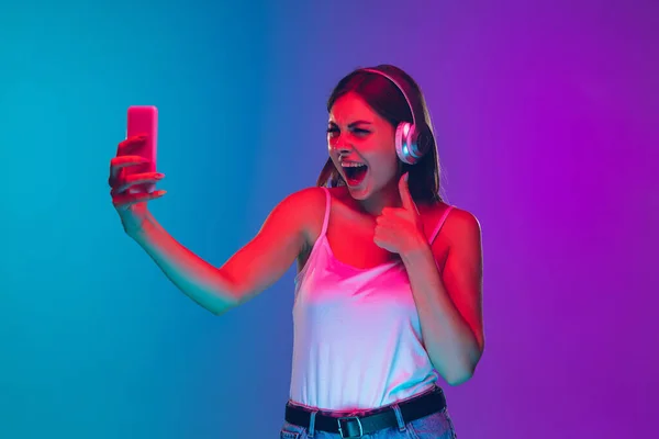 Mulheres brancas jovens retrato isolado no gradiente roxo-azul fundo em luz de néon — Fotografia de Stock