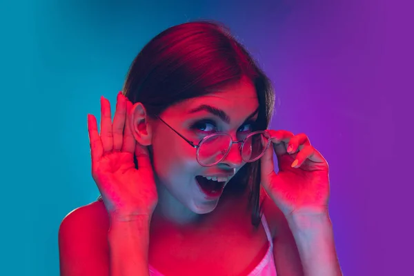 Wanita muda kaukasia potret terisolasi pada gradien ungu-biru latar belakang dalam lampu neon, bioskop, menonton film — Stok Foto
