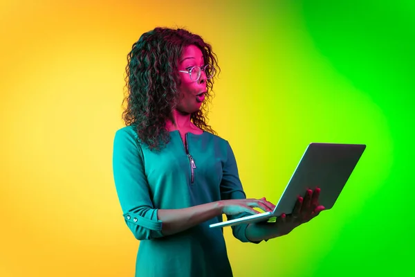 Afroamerikanska unga kvinnor porträtt isolerad på lutning gul-grön bakgrund i neon ljus — Stockfoto