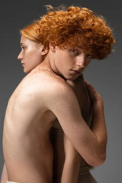 Portrait of beautiful redhead couple isolated on grey studio background. Concept of beauty, skin care, fashion and style