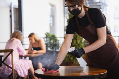 Garson, bir restoranda maske takıyor. Coronavirüs salgını sırasında eldiven takıyor.