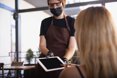 Garson, bir restoranda maske takıyor. Coronavirüs salgını sırasında eldiven takıyor.