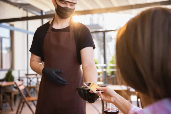 Číšník pracuje v restauraci v lékařské masce, rukavice během pandemie koronaviru — Stock fotografie