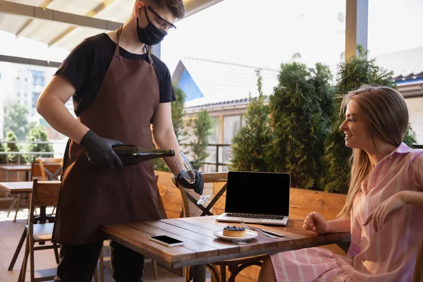 Číšník pracuje v restauraci v lékařské masce, rukavice během pandemie koronaviru — Stock fotografie