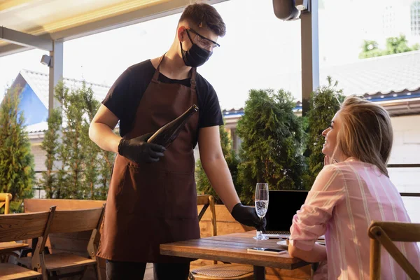 Garson, bir restoranda maske takıyor. Coronavirüs salgını sırasında eldiven takıyor. — Stok fotoğraf