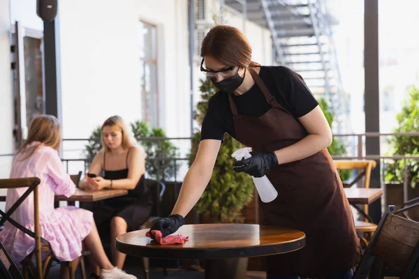 Servírka pracuje v restauraci v lékařské masce, rukavice během pandemie koronaviru — Stock fotografie