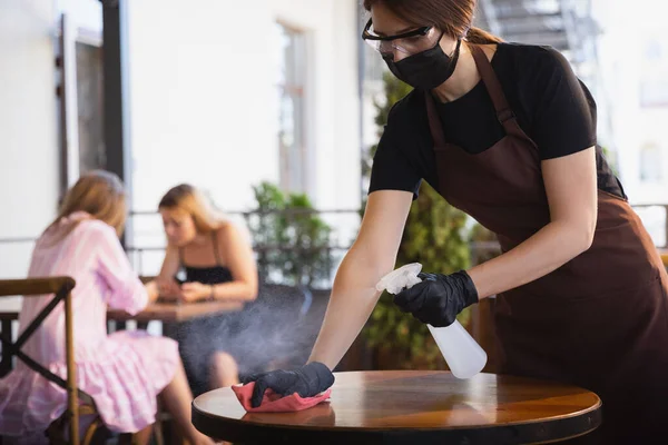 A pincérnő egy étteremben dolgozik orvosi maszkban, kesztyű a koronavírus világjárvány idején. — Stock Fotó