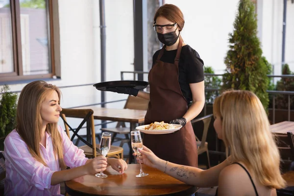 Garson, bir restoranda maske takıyor. Coronavirüs salgını sırasında eldiven takıyor. — Stok fotoğraf