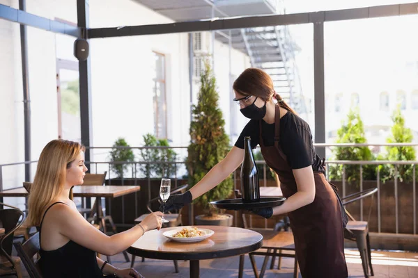 Офіціантка працює в ресторані в медичній масці, рукавички під час пандемії коронавірусу — стокове фото