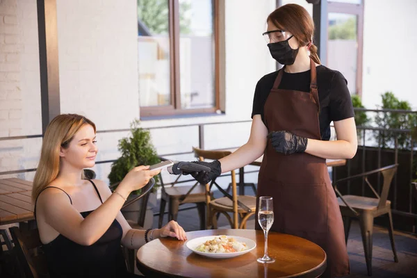 Garson, bir restoranda maske takıyor. Coronavirüs salgını sırasında eldiven takıyor. — Stok fotoğraf