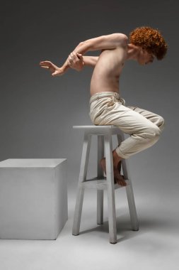 Gri stüdyo arka planında izole edilmiş güzel kızıl saçlı adamın portresi. Güzellik kavramı, cilt bakımı, moda ve tarz