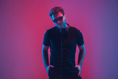 Genç beyaz müzisyen şarkı söylüyor, neon ışıkta dans ediyor.