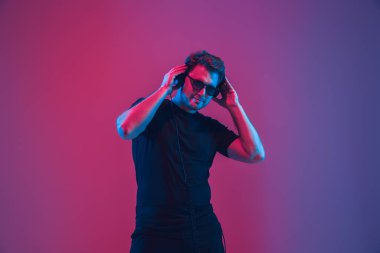 Genç beyaz müzisyen şarkı söylüyor, neon ışıkta dans ediyor.