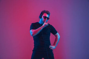 Genç beyaz müzisyen şarkı söylüyor, neon ışıkta dans ediyor.