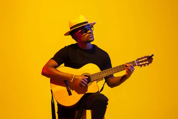 Junger afrikanisch-amerikanischer Musiker singt, spielt Gitarre im Neonlicht — Stockfoto
